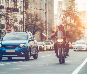 Una moto y varios coches circulando por una carretera mientras otros están apartados
