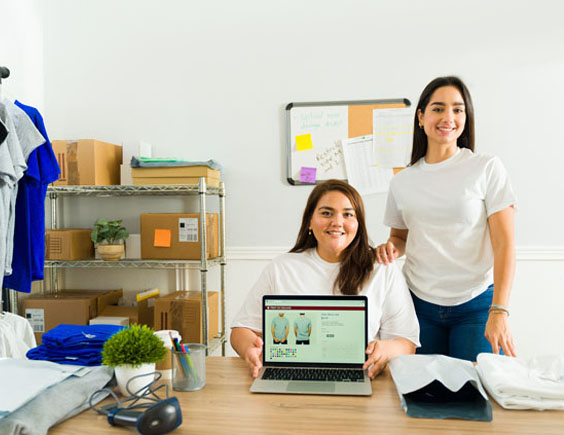 Mujeres jóvenes empresarias mostrando una tienda de camisetas en su ordenador
