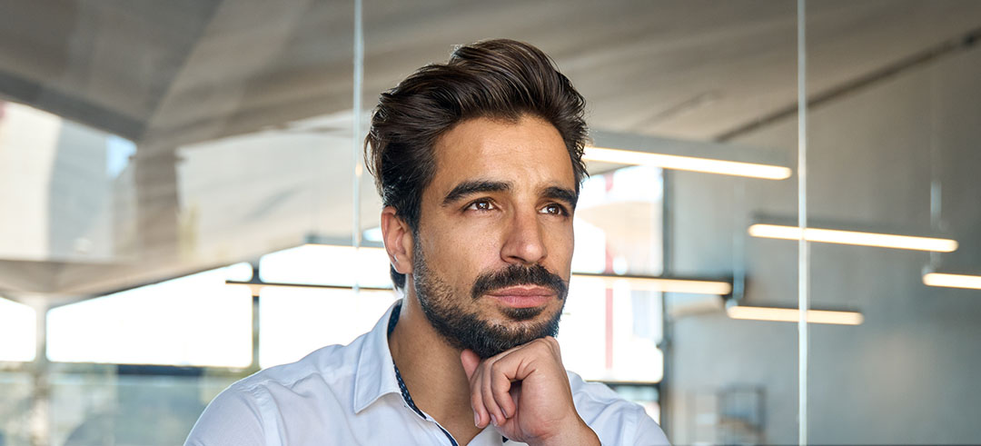 Hombre sentado con la mano en la barbilla, mirando al horizonte