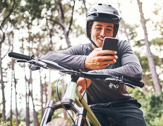 Hombre estacionado con la bicicleta y mirando su smartphone