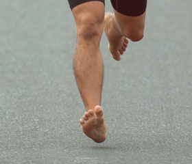 Persona corriendo descalza por una carretera