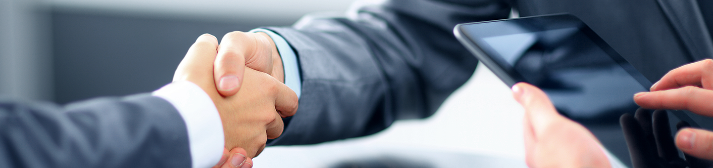Dos personas dándose la mano mientras otra consulta algo en la tablet